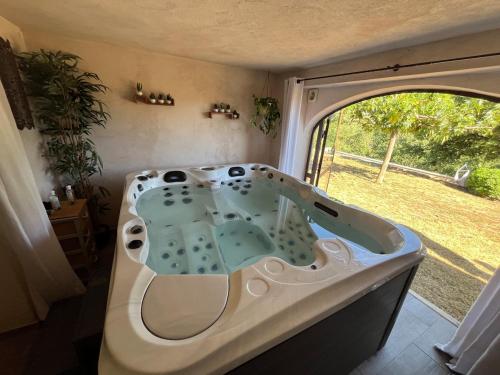 a bath tub in a camper with a view of a yard at Les Coustelines Piscine privée et Jacuzzi in Forcalquier
