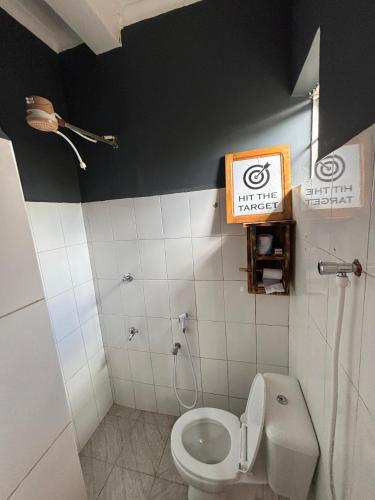 a bathroom with a toilet and a sign on the wall at Balletto Boutique in Arusha
