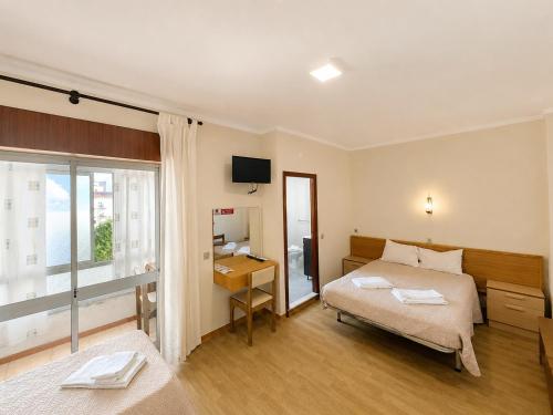 a bedroom with a bed and a desk and a window at Arcádia by Umbral in Fátima