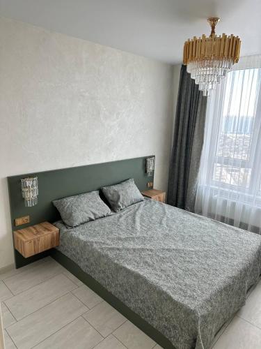 a bedroom with a large bed and a chandelier at ЖК Модерн in Odesa