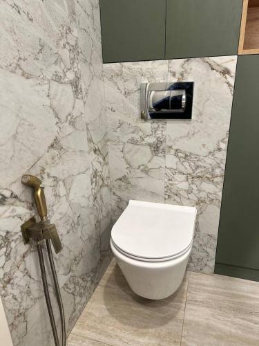 a white toilet in a bathroom with a marble wall at ЖК Модерн in Odesa
