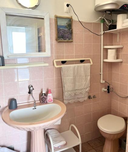 a pink bathroom with a sink and a toilet at Beach House Hvar in Zastražišće