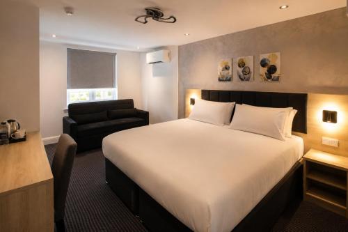 a hotel room with a bed and a chair at Paddington Townhouse Hotel by OYO in London