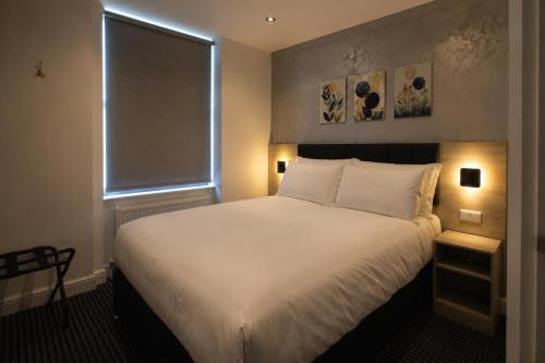 a bedroom with a large white bed with a window at Paddington Townhouse Hotel by OYO in London