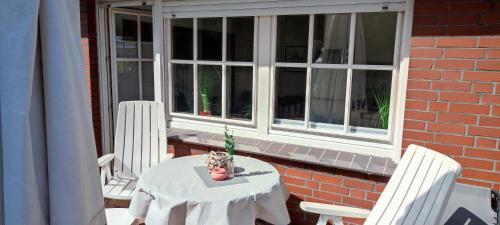 a table and chairs on a porch with a window at Apart Königseiche in Goldenstedt
