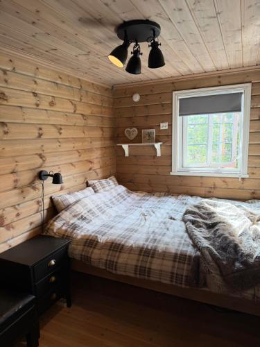 a bedroom with wooden walls and a bed and a window at Hansmoen in Bjorli