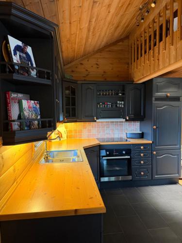 a kitchen with blue cabinets and a wooden ceiling at Hansmoen in Bjorli