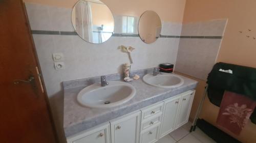 a bathroom with two sinks and two mirrors at Havre de tranquilité en Chartreuse in Saint-Étienne-de-Crossey