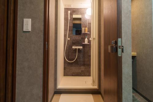 a bathroom with a shower with a glass door at Bonsai Cafe and Stay - B&B Dormitory in Tokyo
