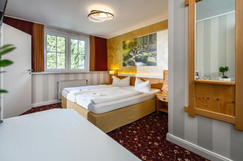 a hotel room with two beds and a window at Flair-Waldhotel Mellestollen in Saalfeld