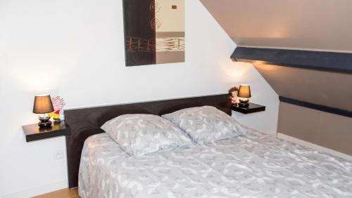a bedroom with a bed and two lamps on tables at Studio confortable à Pédernec - 27m² - Terrasse ensoleillée in Pédernec