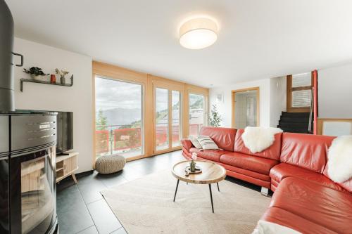 a living room with a red couch and a tv at Bergchalet mit Panoramablick nahe Brienz in Axalp