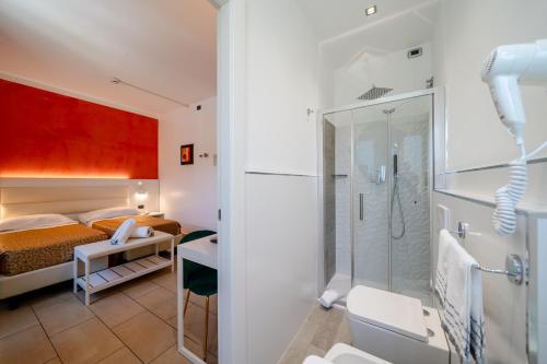 a bathroom with a shower and a bedroom at Hotel Tenda Rossa in Marina di Carrara