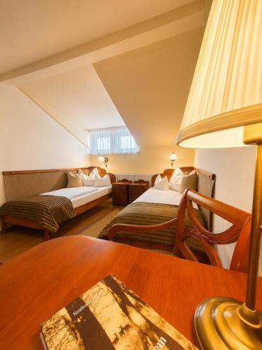 a hotel room with two beds and a table at Csiszárhegyi Vadászház in Karád