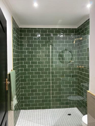 a green tiled bathroom with a shower with a toilet at The Willow Escape in Ballito