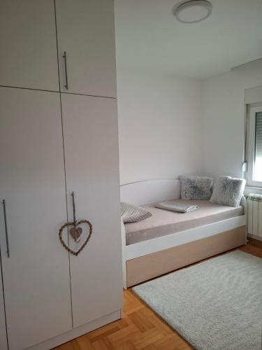 a white bedroom with a bed and a cupboard at Family Apartman Telep Novi Sad - Yard & Free parking in Novi Sad
