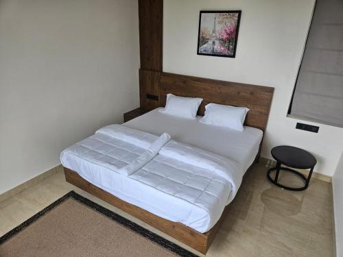 a bedroom with a bed with white sheets and a chair at Indian Bungalows in Vagamon