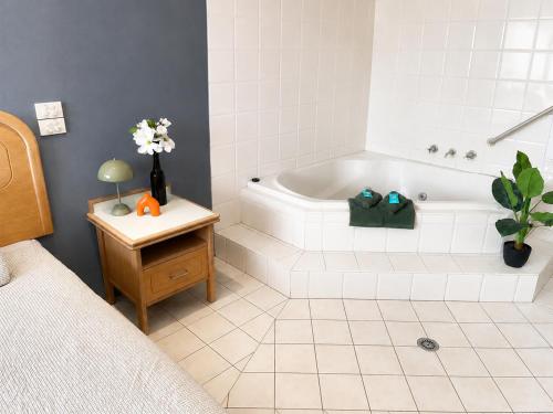a white bathroom with a tub and a bed at Chelsea Motor Inn in Coffs Harbour
