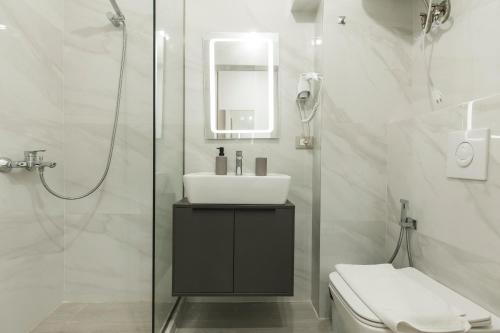 a white bathroom with a sink and a shower at Lotus Apartments in Vlorë