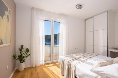a white bedroom with a bed and a large window at Villa Lavanda Deluxe in Rogoznica
