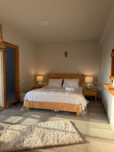 a bedroom with a bed with two lamps and two rugs at Granny's Den - Nathia Gali in Nathia Gali