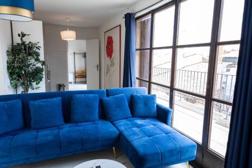 a blue couch in a living room with a large window at Rooftop privé - Clim - Place Carnot - Wifi in Carcassonne