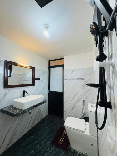 a bathroom with a sink and a toilet and a mirror at The Green View Yala in Tissamaharama