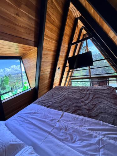 a bedroom with a bed and a large window at Cabaña Con Jacuzzi Privado y Vista a La Montaña in Guarne