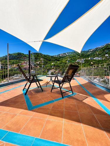 two chairs and a table under an umbrella on a roof at Casa Palomba 41 in Minori