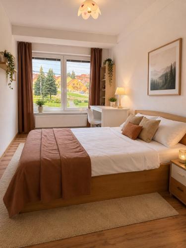 a bedroom with a large bed with a large window at Contact Apartman in Bardejov