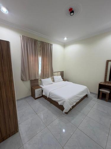 a bedroom with a white bed and a window at شقق ذاعذاع النسيم المخدومة in Al Khuraymī