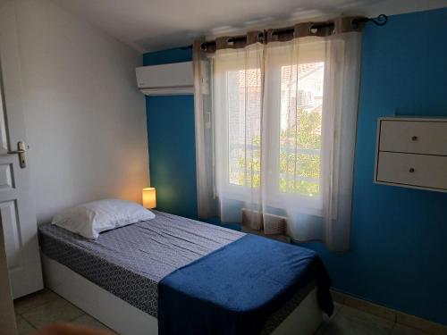a blue bedroom with a bed and a window at Villa climatisée 4-6 pers avec piscine, terrasse & jardin - 2 min plage in Cervione