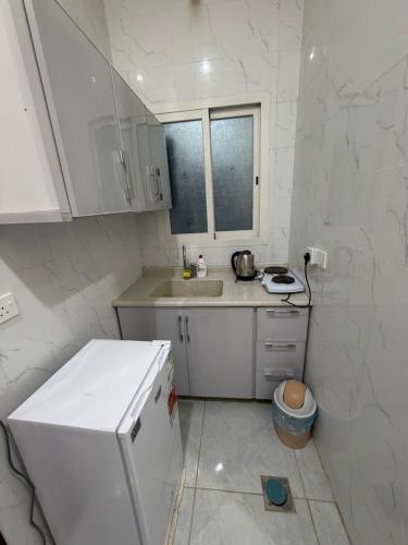 a small white kitchen with a sink and a counter at شقق ذاعذاع النسيم المخدومة in Al Khuraymī