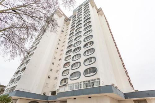 a tall white building with round windows on it at studio world romer in Costa da Caparica