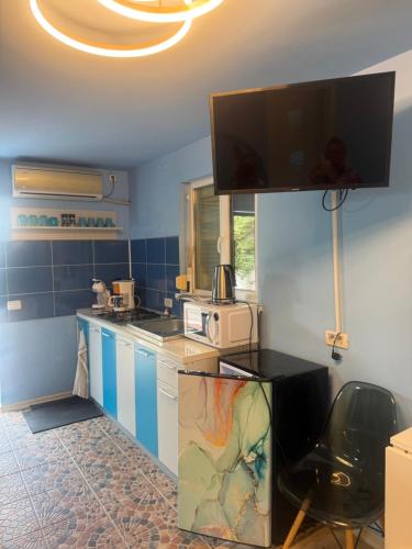 a kitchen with blue and white cabinets and a tv at Studio Bucuria Corbu in Corbu