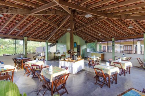 um restaurante com mesas, cadeiras e janelas em Viamar Pousada em Caraguatatuba