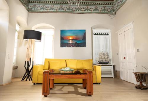 a living room with a yellow couch and a table at "LOS" 1 Neoclassic Harbour View in Symi