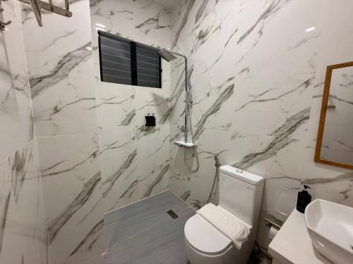 a white bathroom with a toilet and a sink at MBC Hotel in Guinlajong