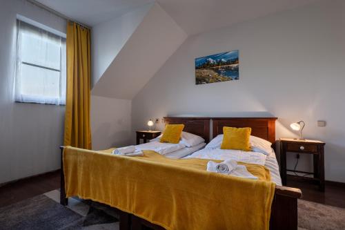 a bedroom with a bed with two yellow pillows at Serenity Residence Hotel & Wellness in Liptovský Trnovec