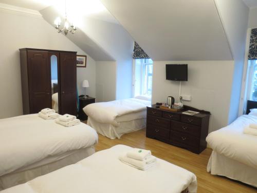 a hotel room with two beds and a television at Thornfield Guest Residence in Edinburgh