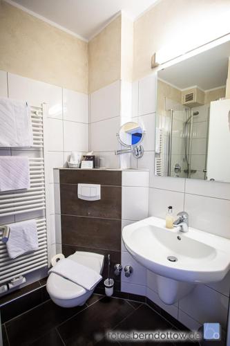 a white bathroom with a sink and a toilet at Hotel Spessartstuben in Haibach
