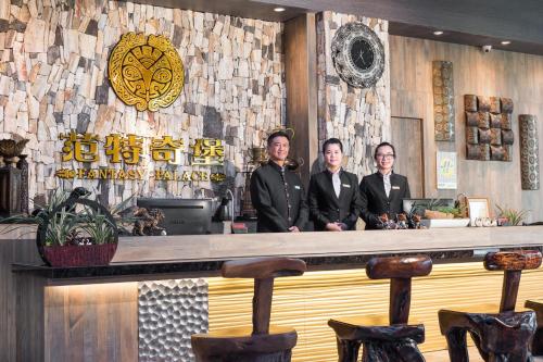 a group of three men standing behind a bar at Fantasy Palace in Yuchi