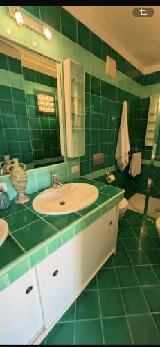 a green tiled bathroom with a sink and a mirror at Amore di Mare in Cagliari