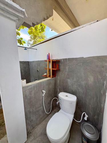 a bathroom with a white toilet in a wall at ThePopos in Arugam Bay