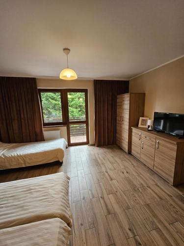 a hotel room with two beds and a flat screen tv at Pokoje DARMAT in Stegna