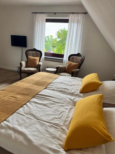 a bedroom with a large bed with two chairs and a window at Ferienwohnung Klahn Neue Tiefe in Neue Tiefe Fehmarn