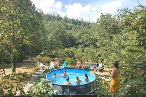 a group of people sitting around a swimming pool at La Clef De Voute Amethyste in Saint-Genest