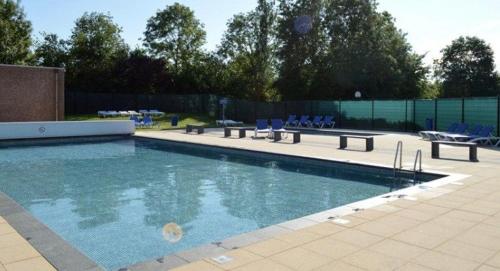 a large swimming pool with blue chairs at Het lila huisje in Herkingen