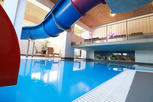 a swimming pool with a slide in a building at alla Papa in Obernzenn