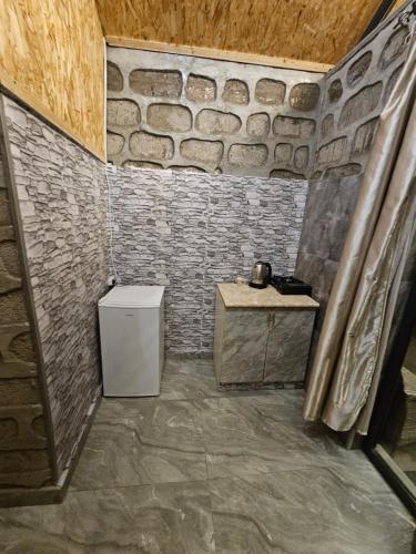 a bathroom with a toilet and a stone wall at Old Goris Hotel in Goris